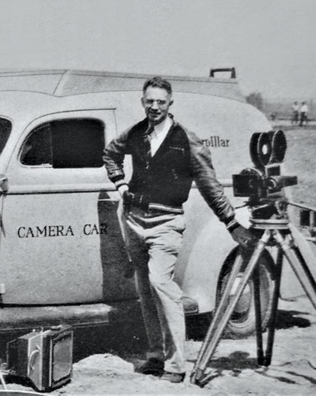 Fred R. Jolly posed with several of the cameras he carried around the United States in the 1940 Ford V-8 Deluxe sedan delivery pictured behind him. The sedan delivery was named the “Caterpillar Camera Car” as Jolly was photographing and filming for the machinery company