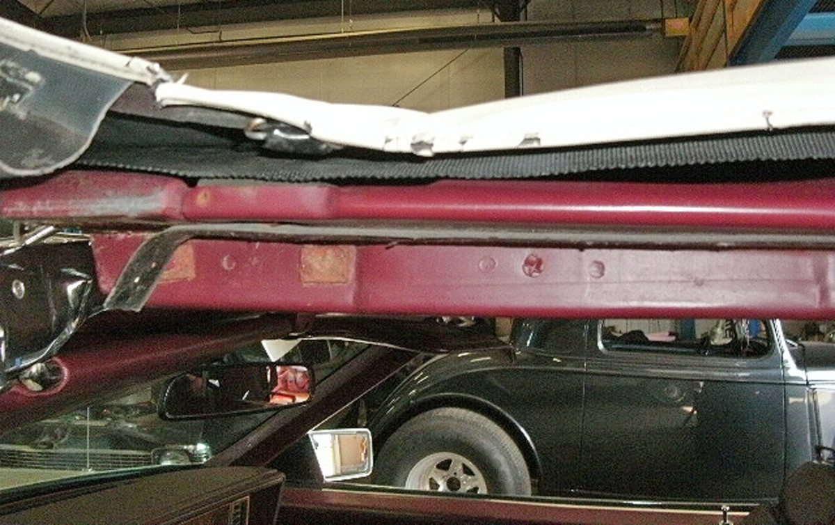 Another view of the convertible top pulled away from the side rail to remove the top moldings. The end of the convertible top cable is again visible.