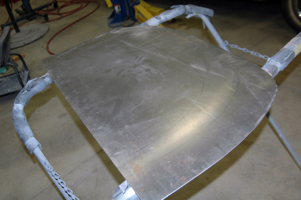  An oversized piece of flat stock is placed against the body so Leonard Schrock can trace the shape of the wheel opening and cut the metal to shape. The trace line is very faint.