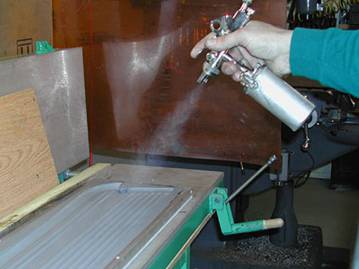  Above, Before the urethane is poured, a release agent is sprayed in the mold. Below,The backing plate suspending the sill mat’s metal core is lowered. The black clips hold the metal core. Once the urethane is poured into the mold, the top platen can be lowered and pressure can be applied to solidify the urethane so it becomes rubber-like.
