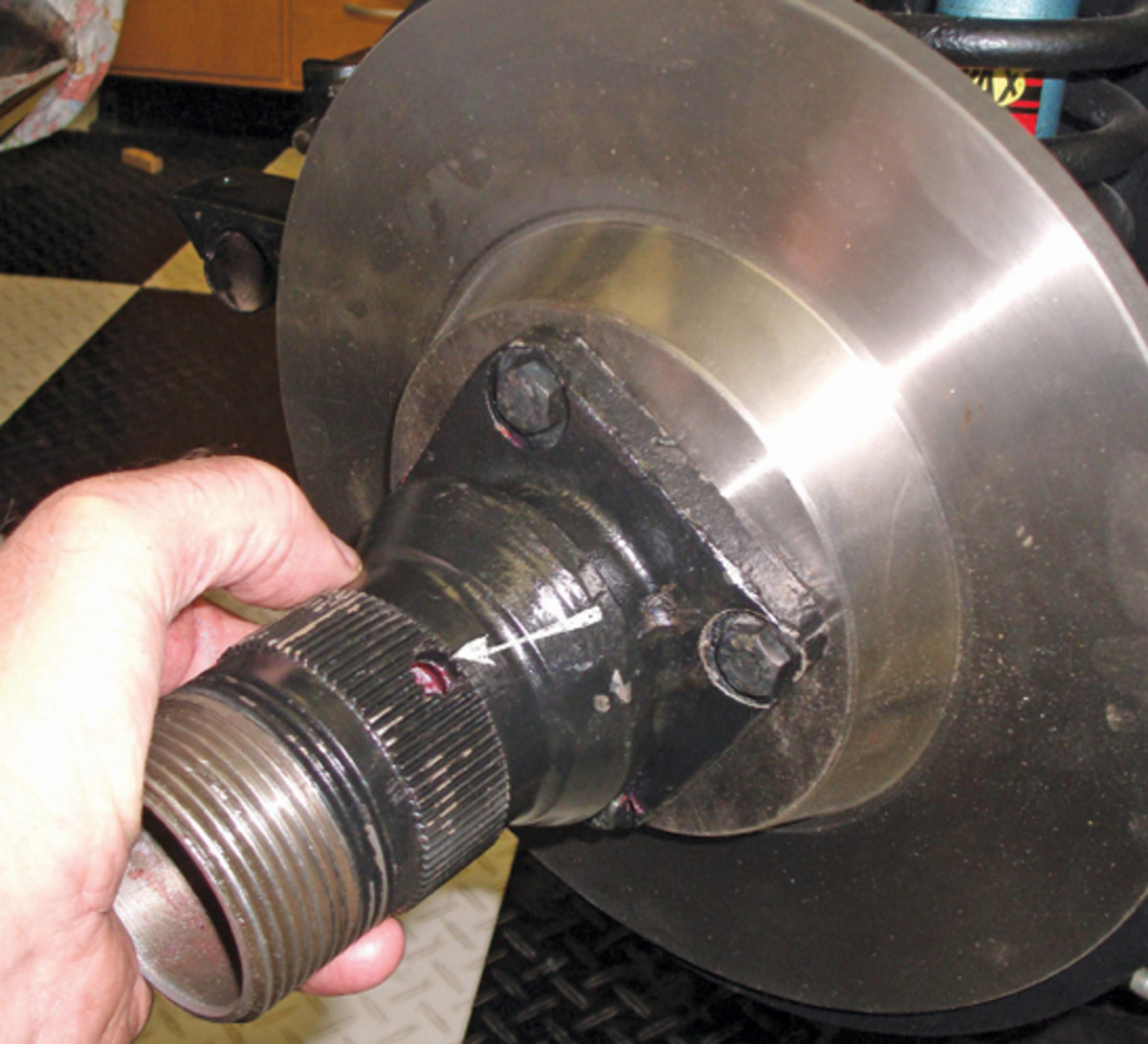 With all bearings, felt seals, dust covers and shields in place, the hub and rotor assembly can be slid onto the stub axle. This may push the small bearing out, but it can be pushed back in. The arrow points to the cotter pin install hole.