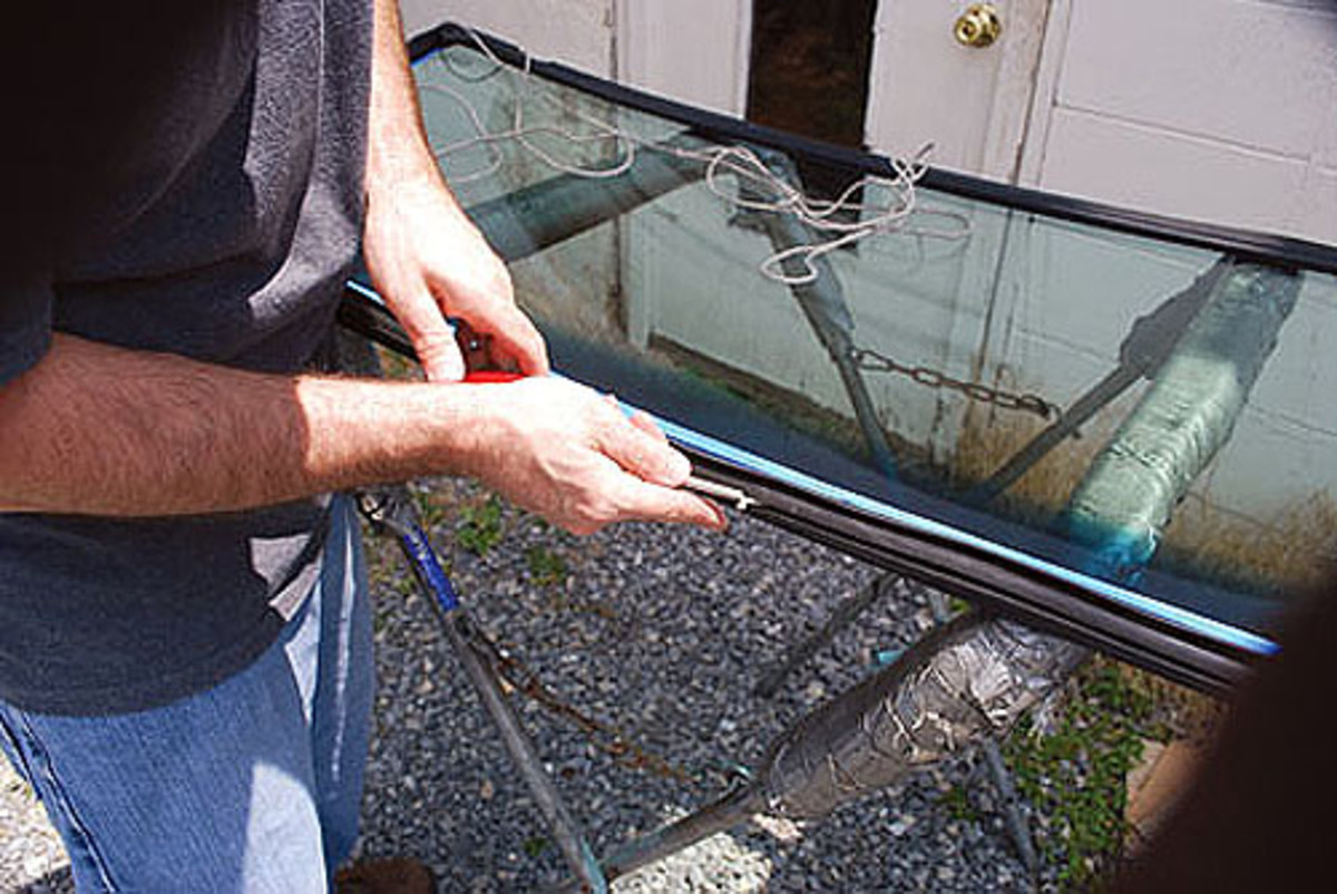  Next, the Norman’s boys cleaned the new glass and fit the gasket around the glass. Masking tape was used to hold the gasket in position while the rope was fed into the gasket channel, which will be used to pull the gasket over the windshield frame ridge once the glass is set in position. Here, Brian is feeding the rope into the channel.