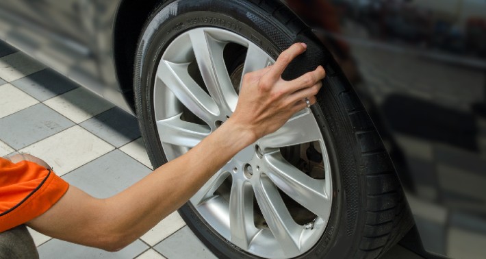 A person's arm spraying a tire with tire shine
