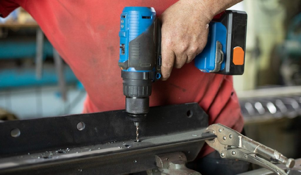 using a cordless drill to work on a car