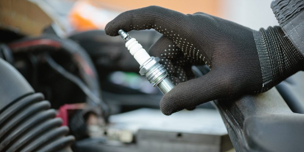 New car spark plug in auto electrician hand close up.