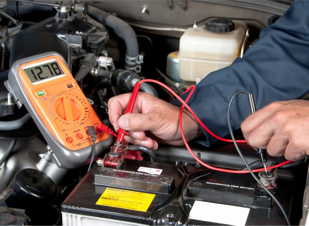 A mechanic checking a car battery's voltage