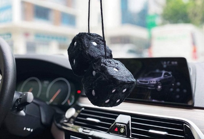 A black fuzzy dice hanged in a window of a car