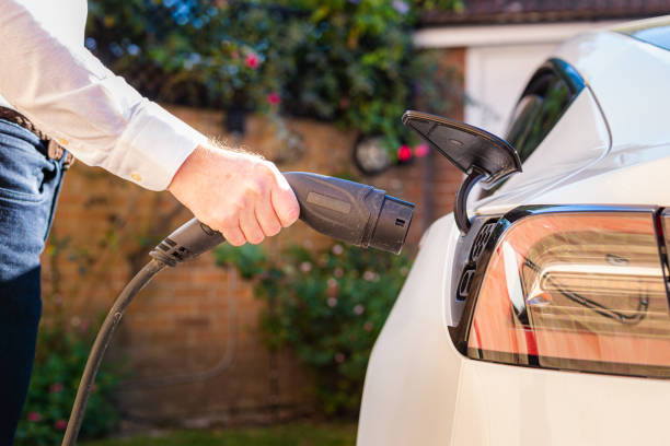 Color image depicting a man charging his electric vehicle with a portable ev charger