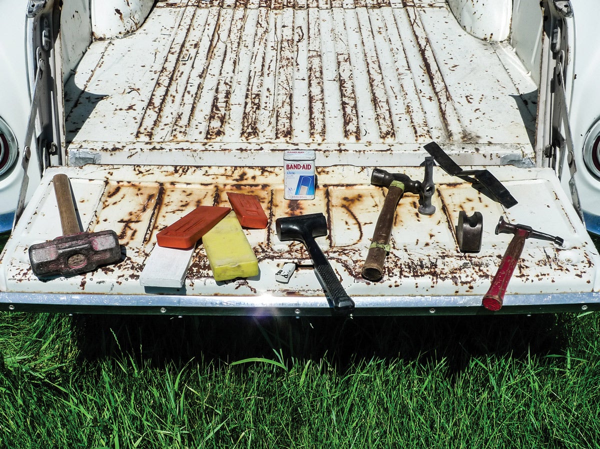We’ll be working in the weeds, but this time not in pouring rain. Here, on the tailgate of some old wreck, we have some generic items that we’ve thought to bring along for parts pullin’.