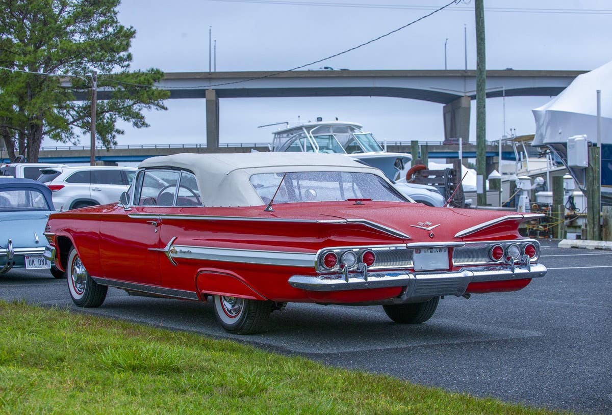 A vintage red Chevrolet Impala cruises along the waterfront near the Kent Island Yacht Club during the Chesapeake Bay Motoring Festival, which features classic vehicles, boats, and family activities each summer. Get advanced discounted tickets at www.chesapeakebaymotoringfestival.org.